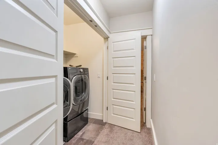 Dedicated laundry area featuring a shelf for storage, paneled doors, and tiled flooring
