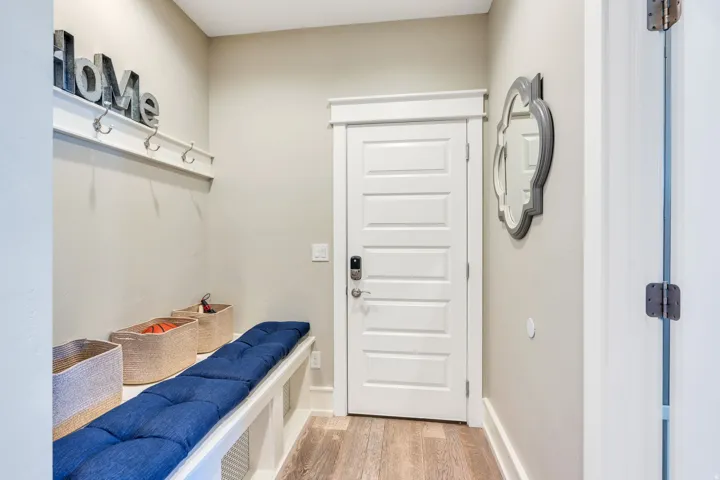 Built-in bench seating with cubby storage, panel door with smart lock, wall-mounted coat rack, light wood-finish flooring, and neutral wall tones