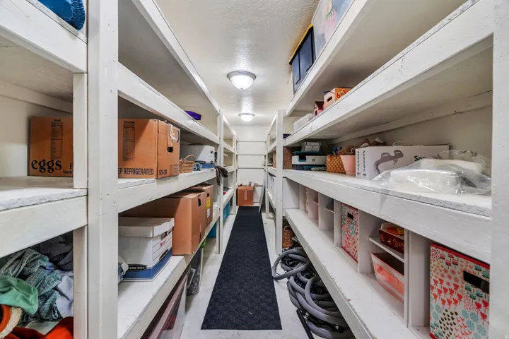 Extensive storage room featuring multiple rows of white wooden shelving spanning the length of the room