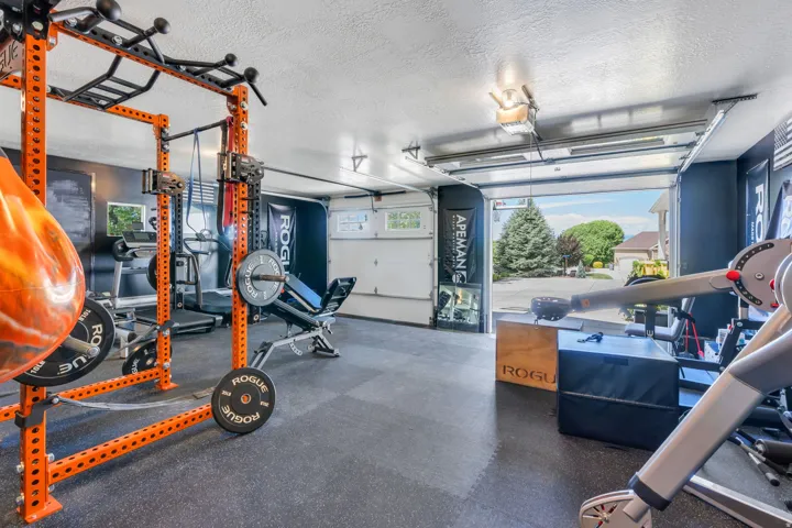 Garage interior featuring a rubber mat flooring system, dark wall paint, and overhead lighting