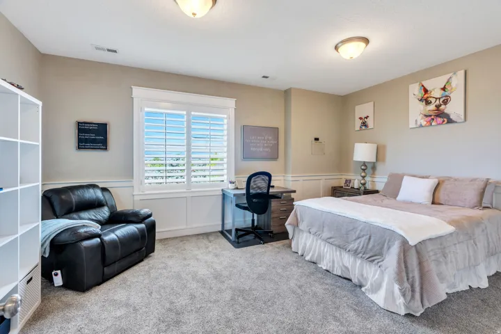 Carpeted room featuring a large window with white plantation shutters, white wainscoting, and neutral wall paint