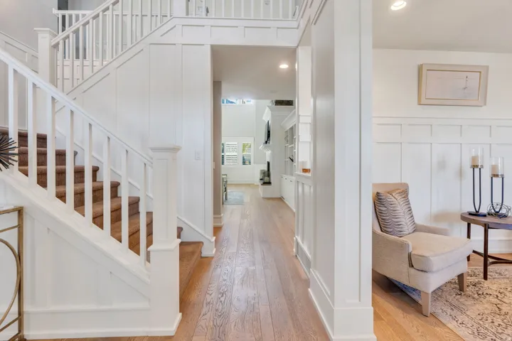 Foyer featuring a grand staircase with white balusters and carpeted treads, wood-finish flooring, recessed lighting, and white board and batten wall detailing