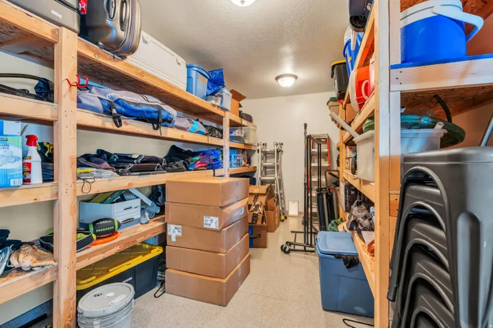 Dedicated storage room featuring extensive wood shelving, overhead flush-mount lighting, and durable flooring