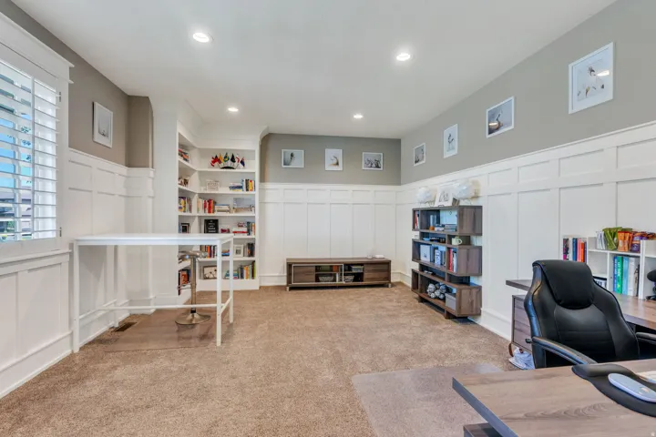 Spacious room featuring extensive wainscoting, recessed lighting, and plush carpet flooring