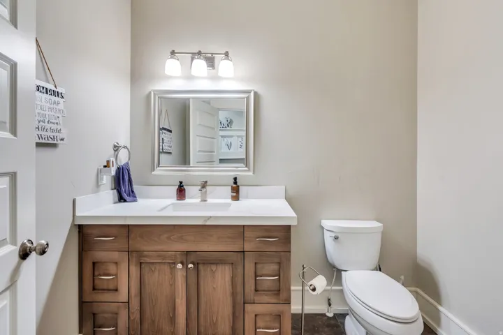 Bathroom featuring a wood-finish vanity with a white countertop, an undermount sink, a chrome-finish faucet, and a wall-mounted mirror