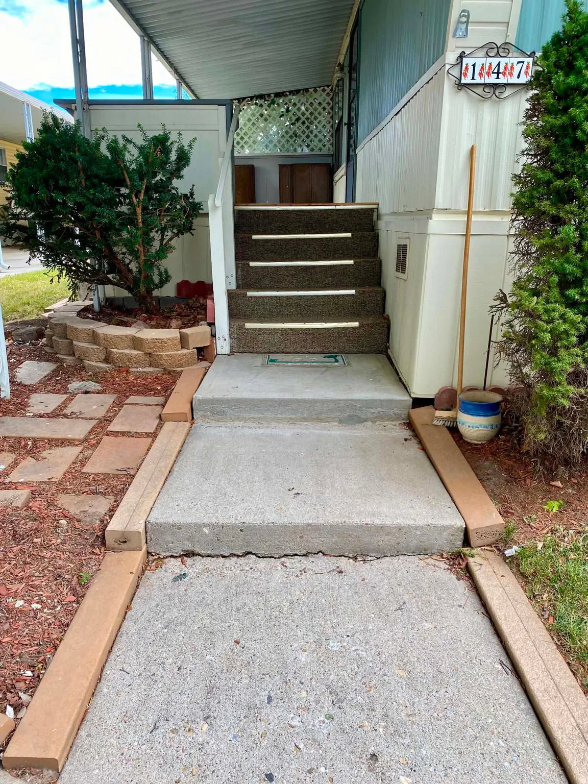 Concrete walkway leading to carpeted entry steps
