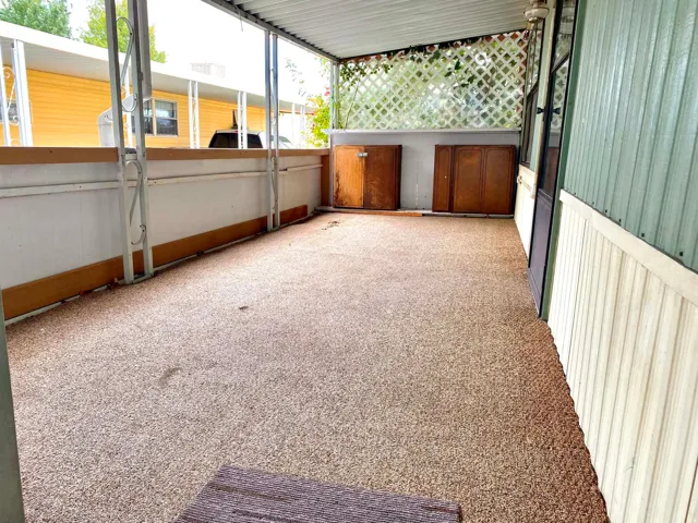 Covered patio featuring a textured floor surface, white lattice detailing, and built-in storage units