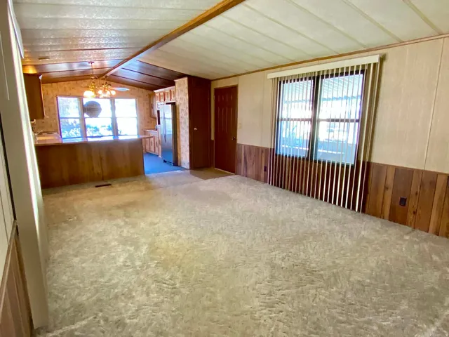 Spacious room featuring light-toned carpeting and wood-paneled wainscoting
