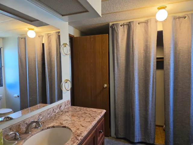 Bathroom vanity featuring a polished stone countertop, undermount sink, and chrome faucet