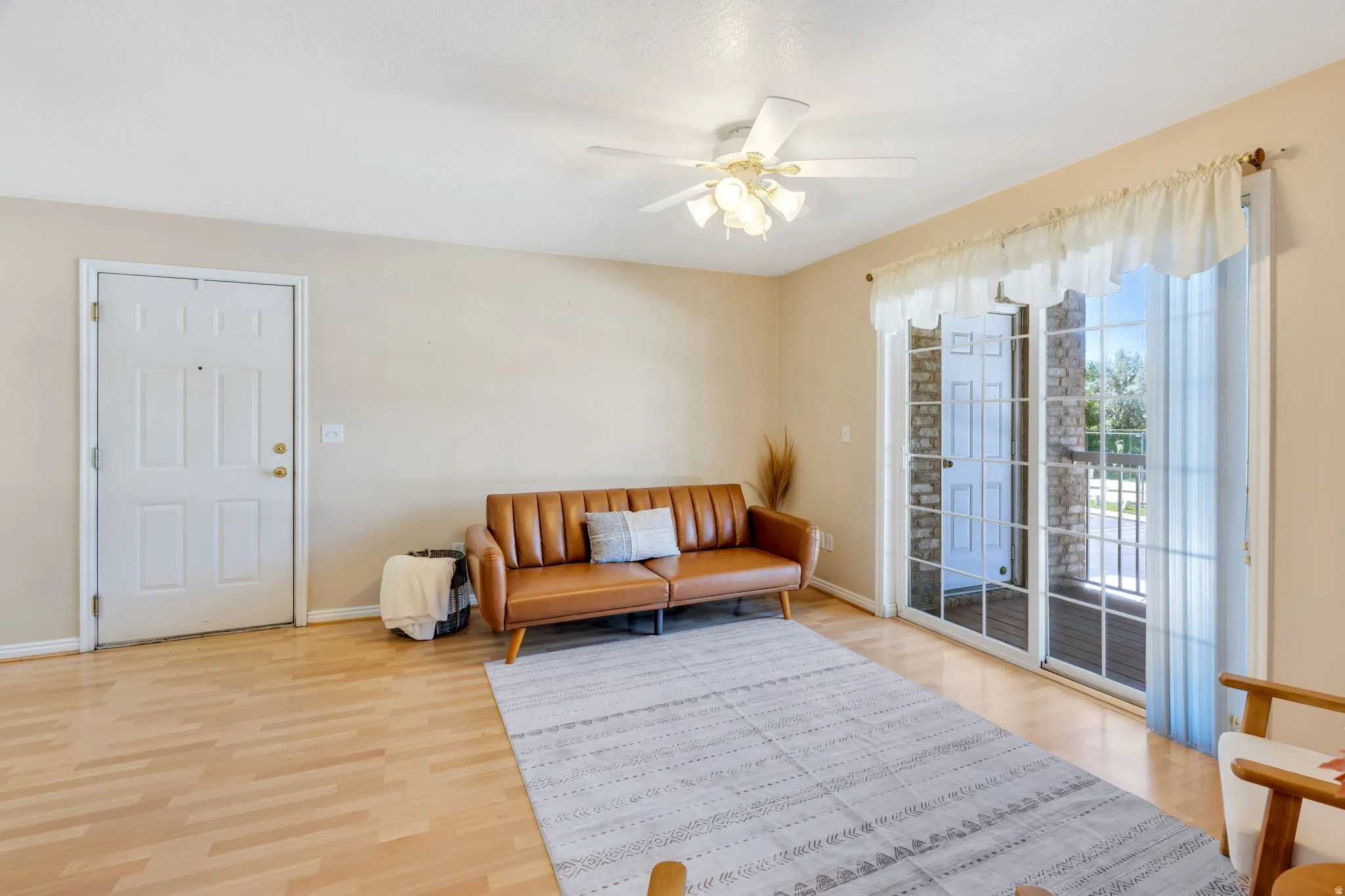 Open-concept living area with wood-finish flooring, Glass Doors out to Balcony.