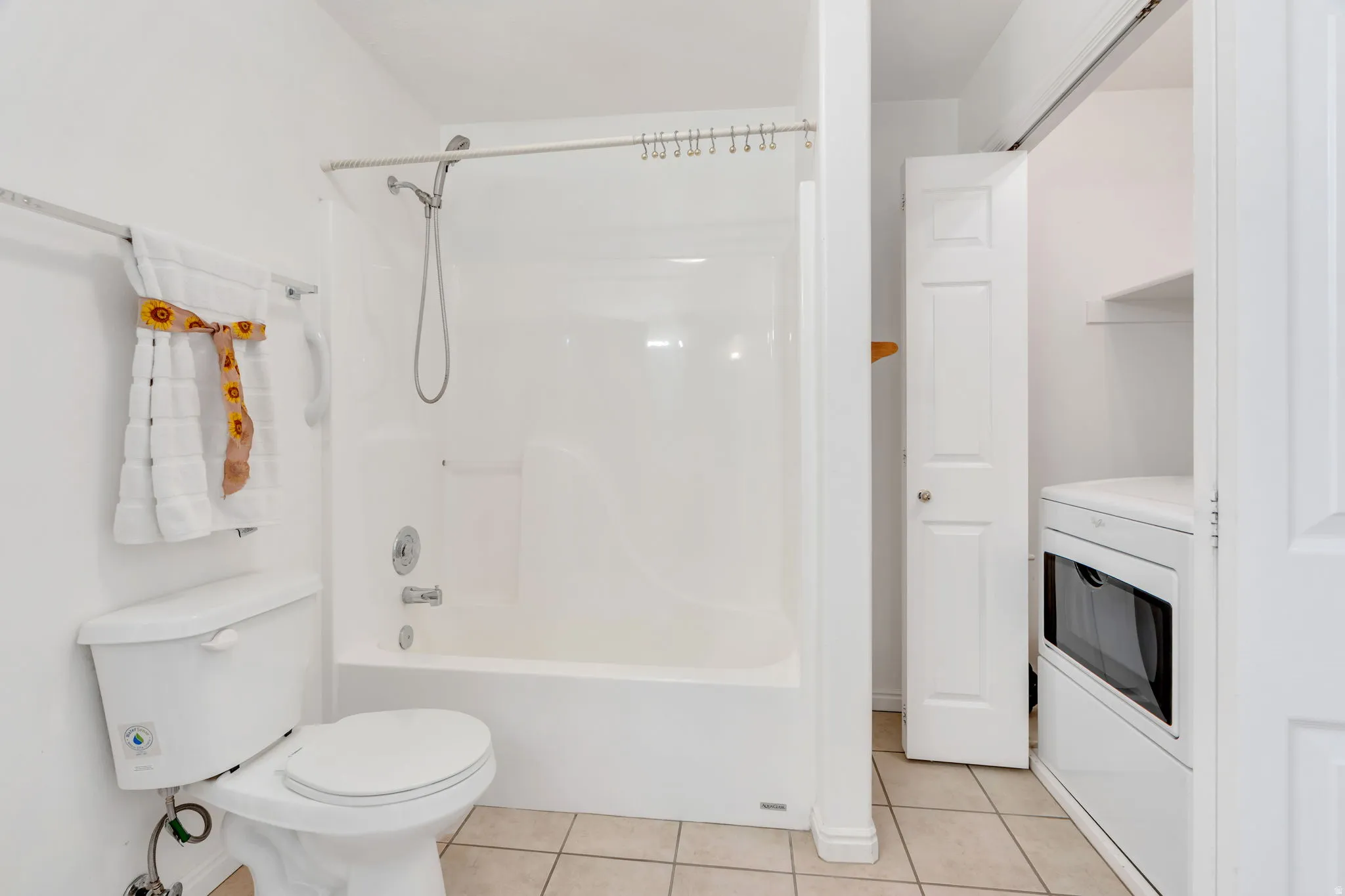 Bathroom featuring a white toilet, white tub-shower combination, and light-toned floor tiles