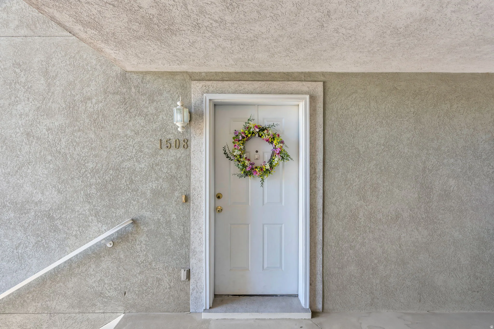 Up short flight of stairs. White paneled entry door with brass-finish hardware