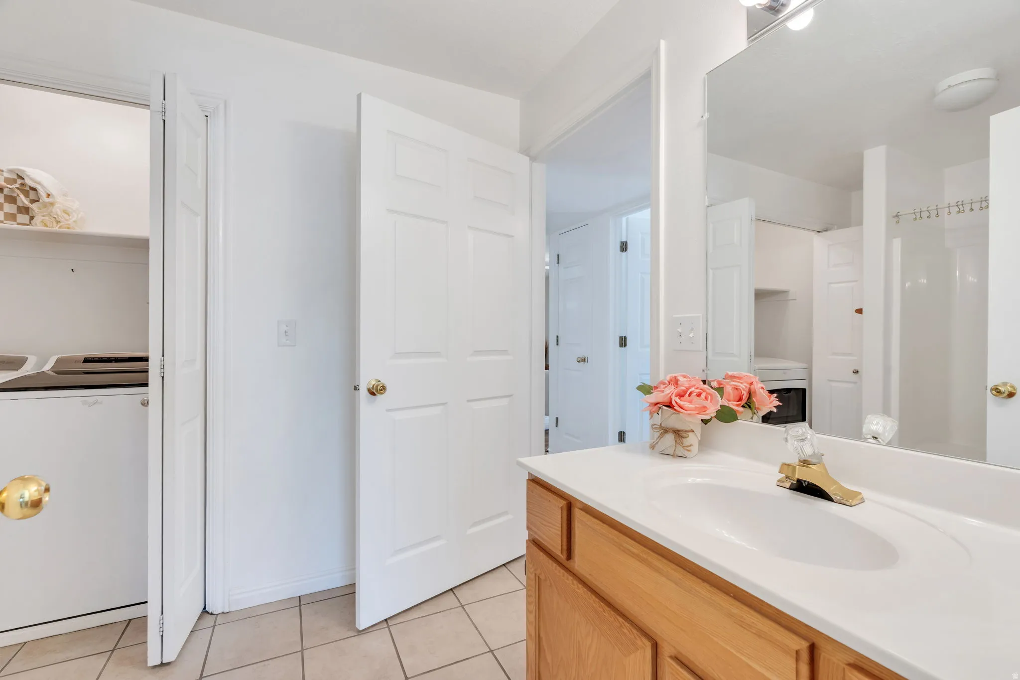 Inside of Bathroom featuring a single vanity with a white countertop and integrated sink, a large wall-mounted mirror, and tile flooring
