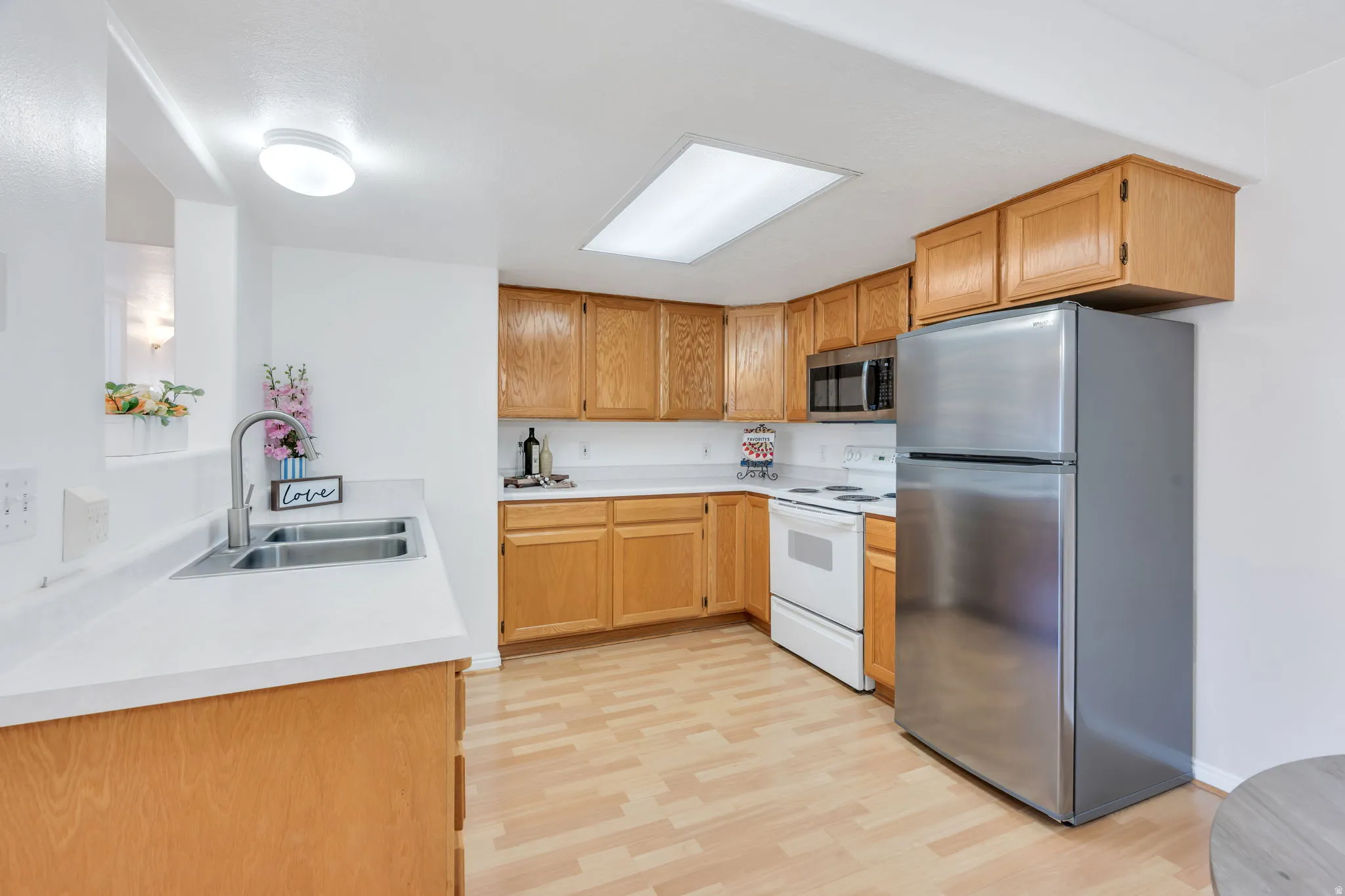 Kitchen featuring wood-finish flooring, light wood cabinetry, and white countertops