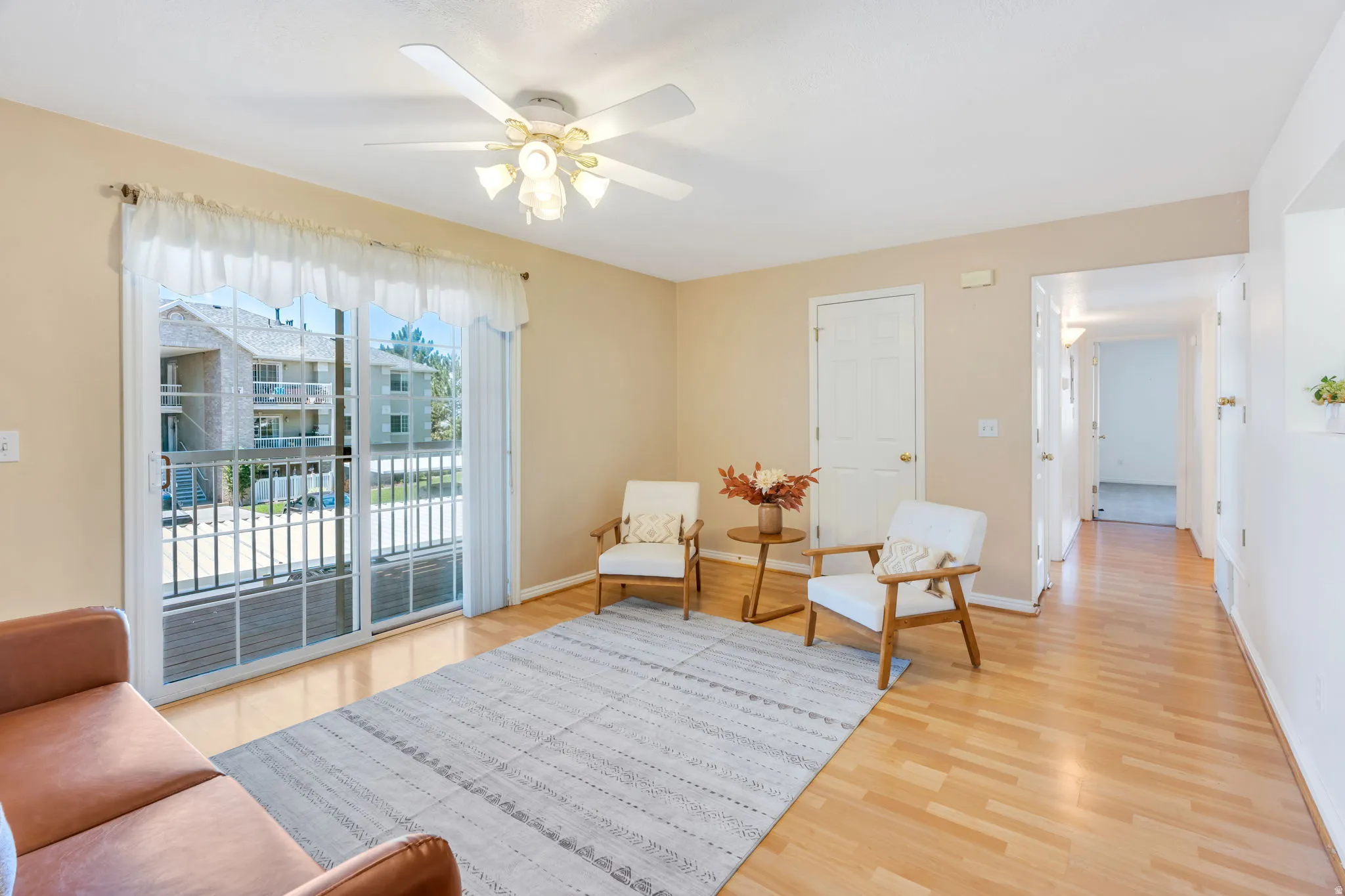 Living area featuring wood-finish flooring, a ceiling fan with integrated lighting, and neutral wall paint