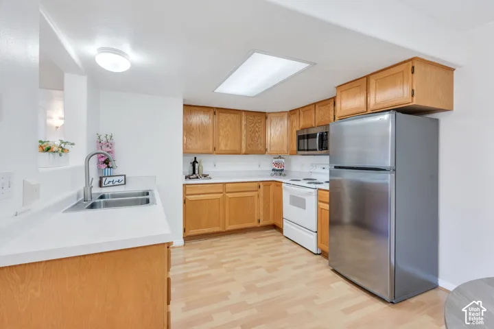 Kitchen featuring wood-finish flooring, light wood cabinetry, and white countertops