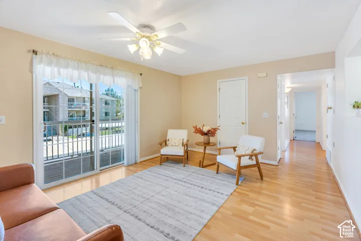 Living area featuring wood-finish flooring, a ceiling fan with integrated lighting, and neutral wall paint