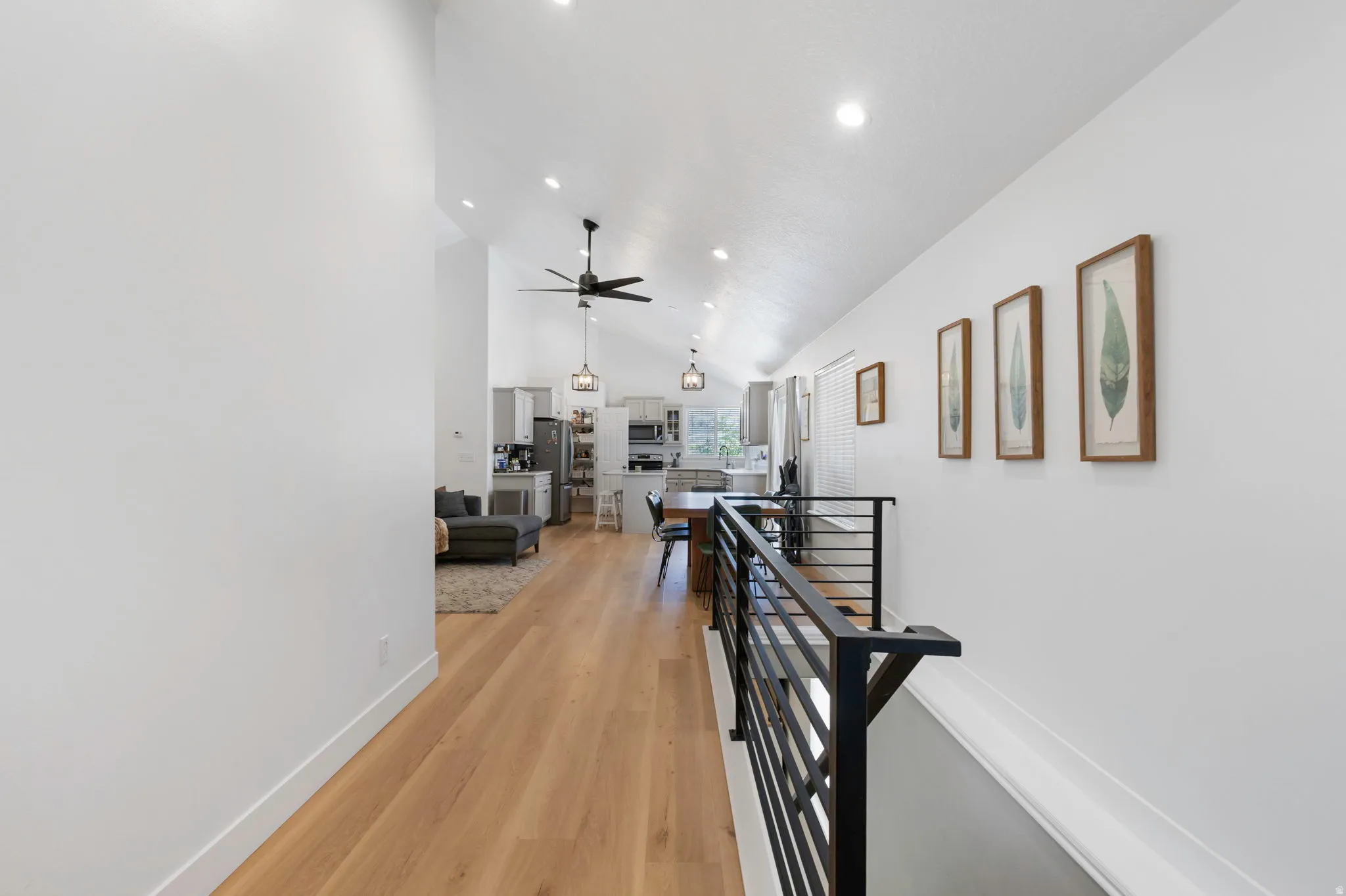 Open concept living space featuring vaulted ceilings, light wood-finish flooring, recessed lighting, and a modern horizontal bar railing