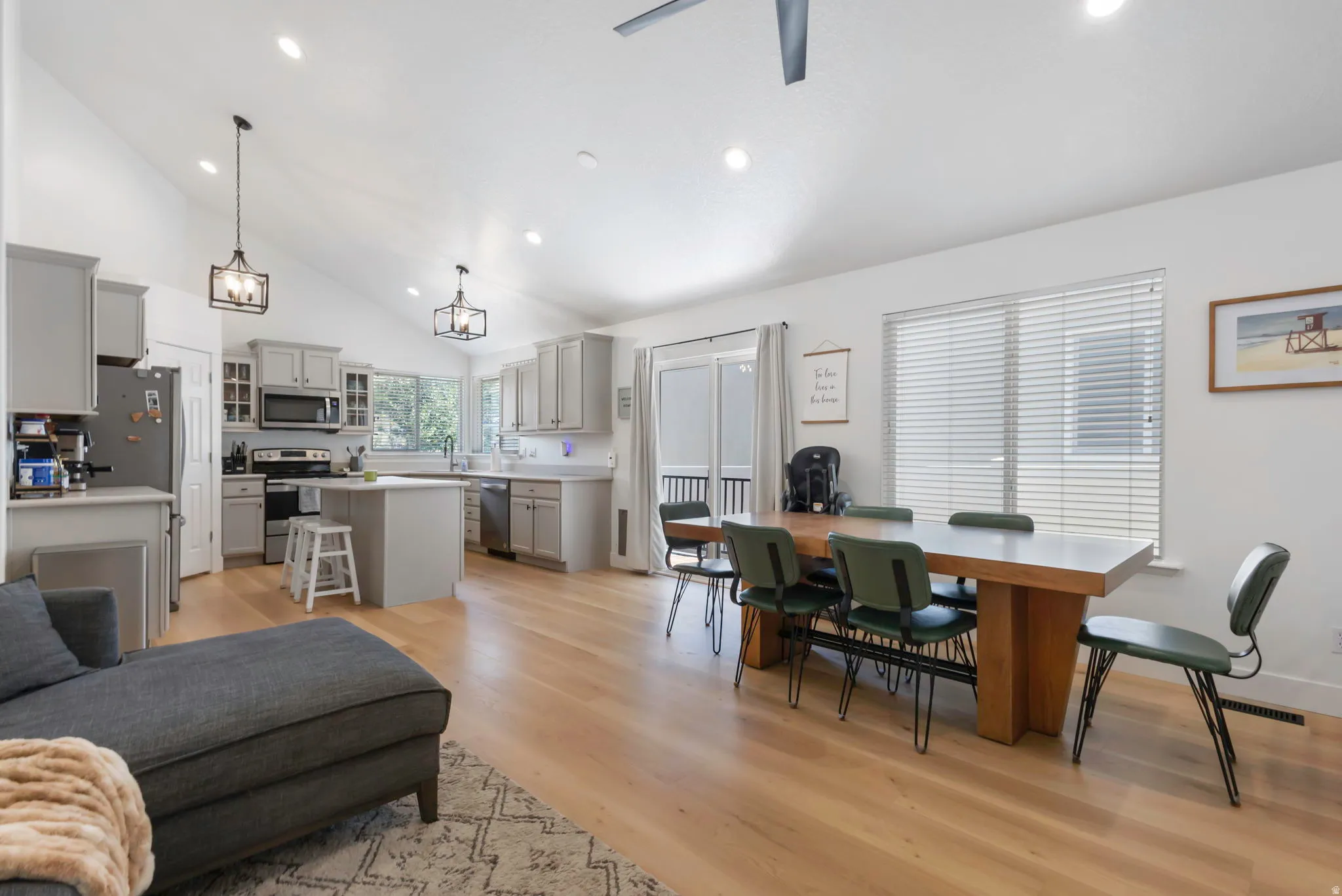 Open-concept living area featuring light wood-finish flooring, vaulted ceilings, and recessed lighting