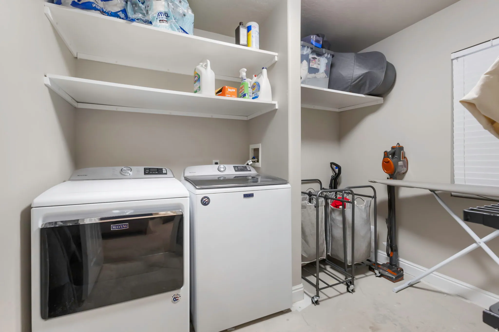 Dedicated laundry area featuring a full-size washer and dryer, ample shelving for storage, and light-toned walls