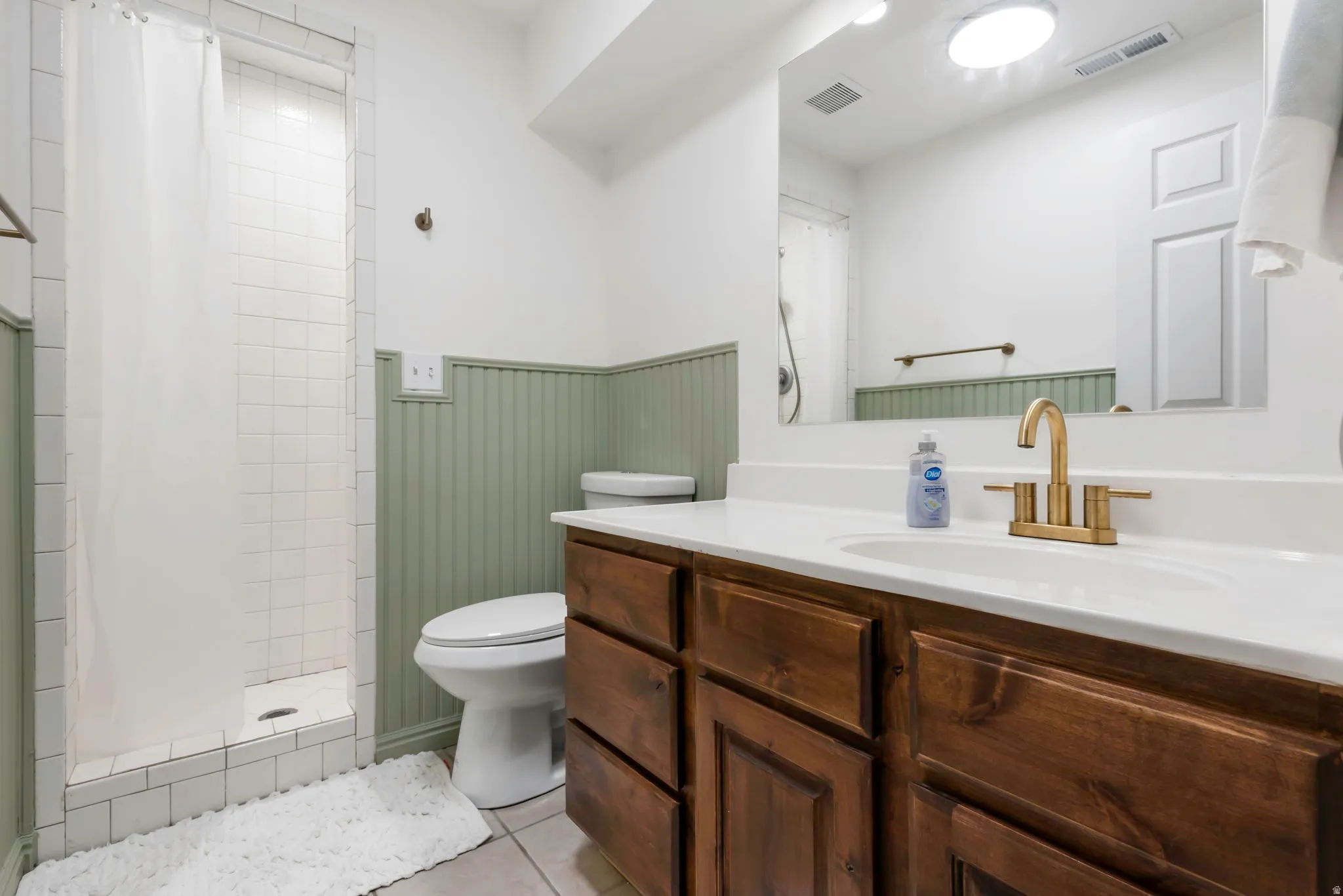 Bathroom featuring a single vanity with wood cabinetry, a white countertop, and a brass-finish faucet