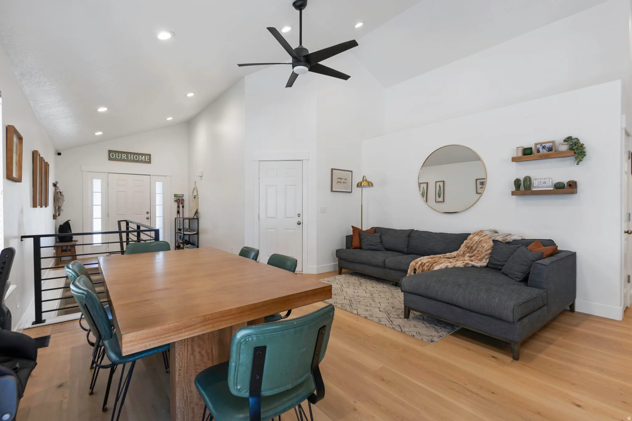 Spacious great room featuring high vaulted ceilings, light wood-finish flooring, recessed lighting, and a modern ceiling fan