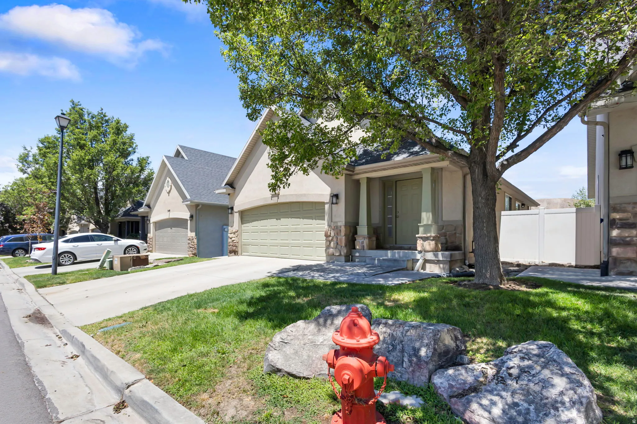 Stucco exterior featuring stone accents, a covered front entry, and an attached two-car garage