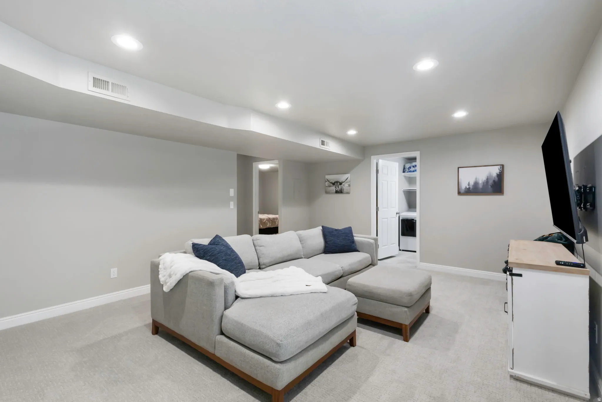 Finished living area featuring light gray carpeting and recessed lighting