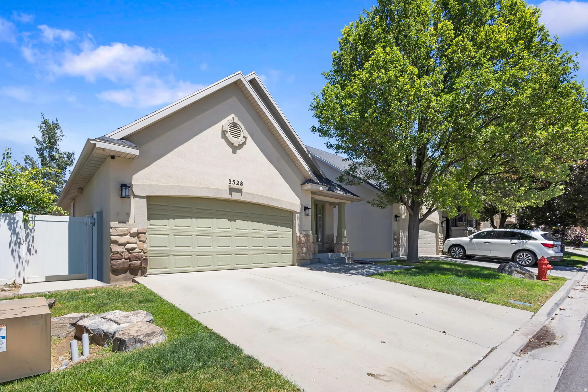Stucco exterior residence featuring an attached garage, stone accents, and a concrete driveway