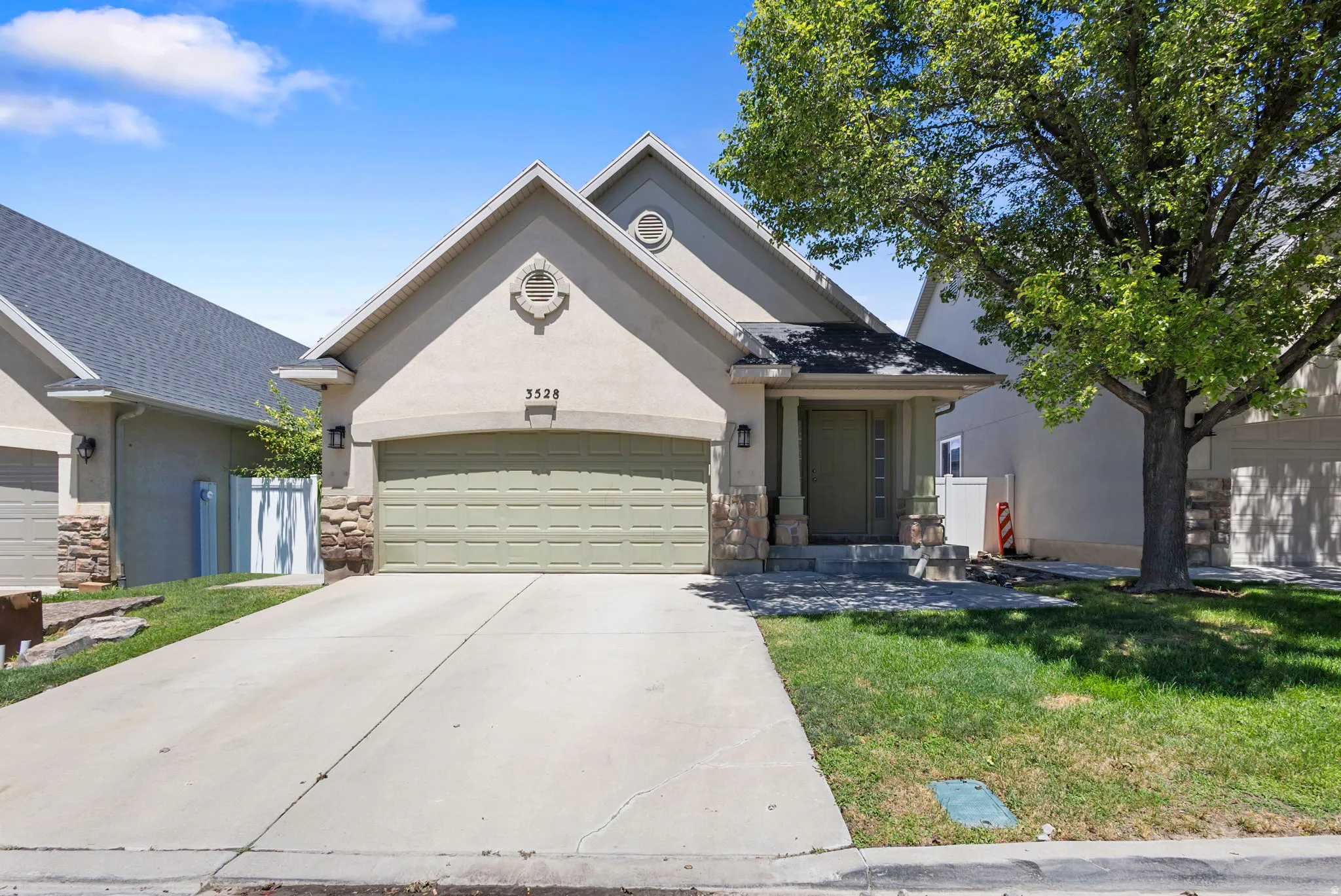 Ranch-style residence featuring a stucco exterior with stone accents, a two-car garage, and a covered entry