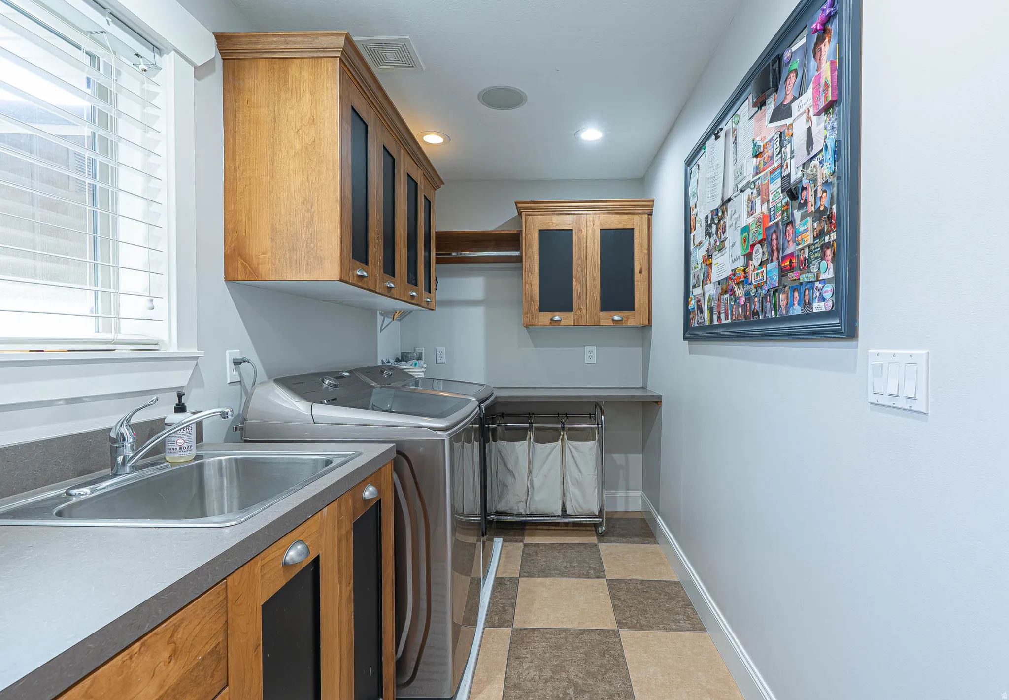Spacious dedicated laundry space featuring a utility sink, wood cabinetry, and a checkerboard floor pattern