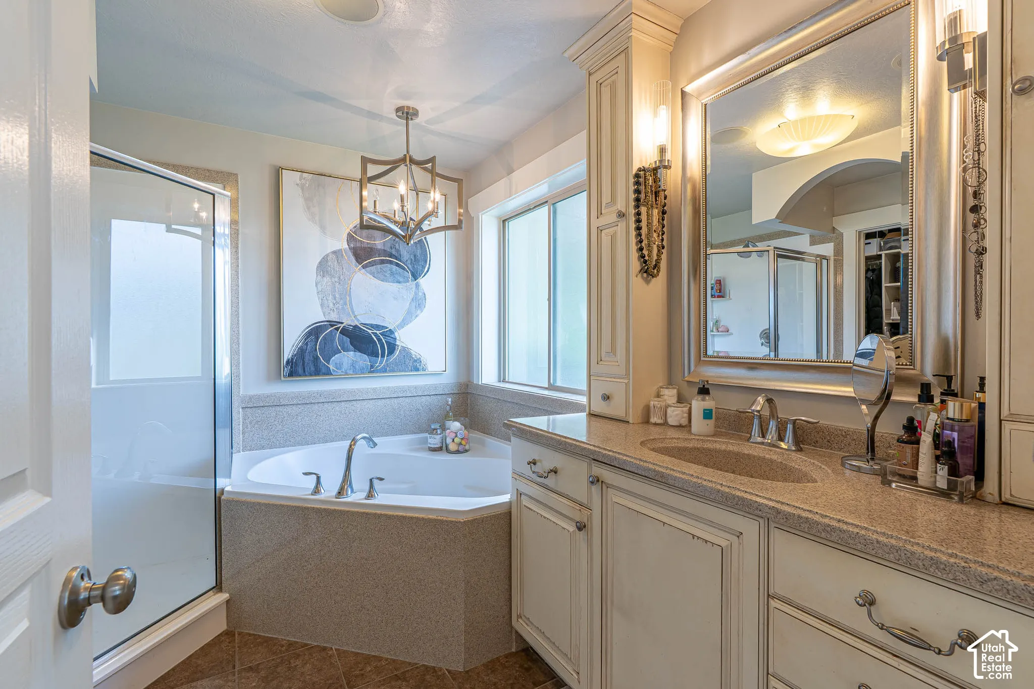 Primary bathroom featuring a corner soaking tub with jets, separate glass-enclosed shower, vanity with undermount sink, and new recessed lighting