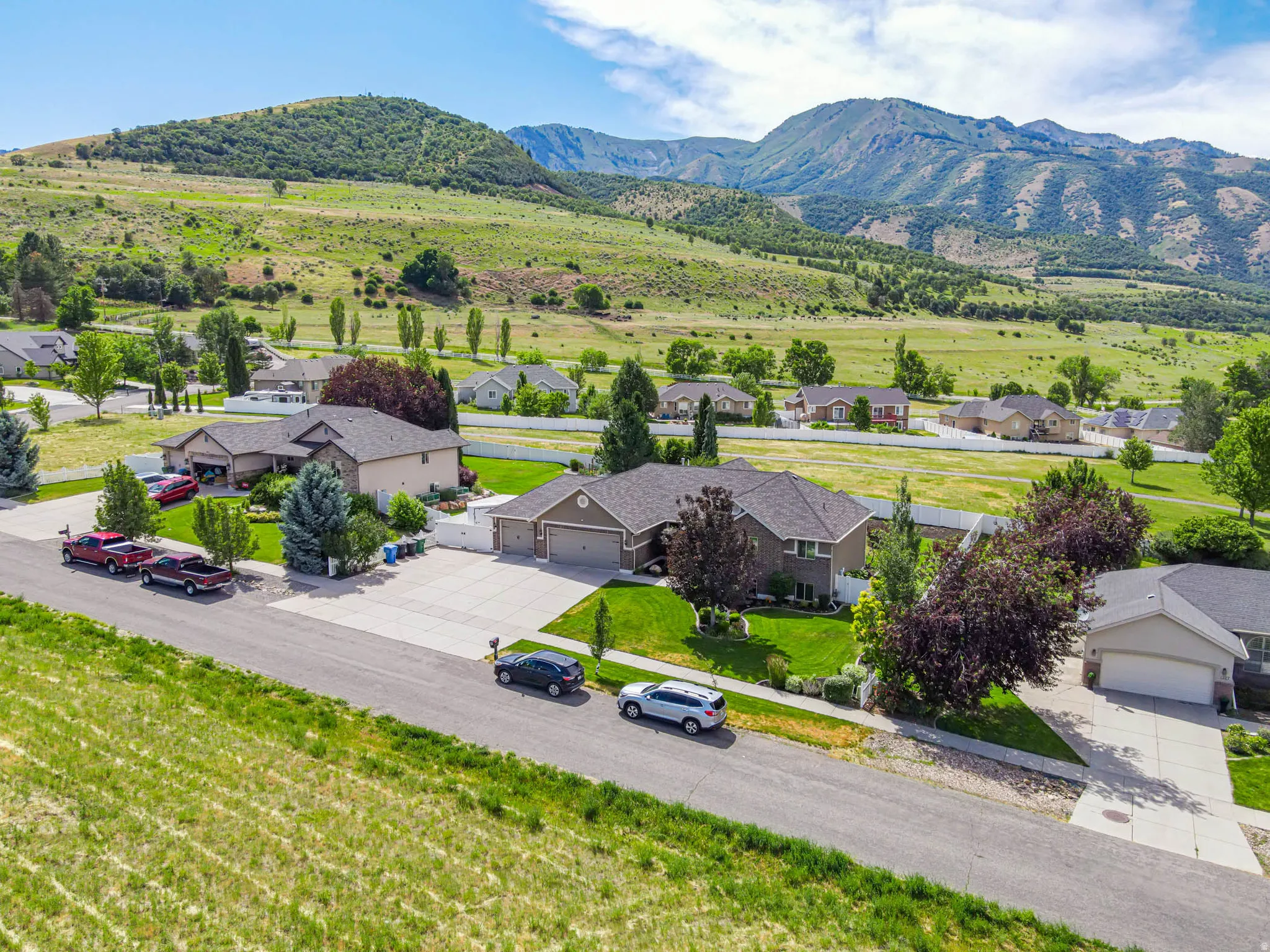 Spacious residential property featuring a stone and siding exterior, multi-car driveway, and stunning mature landscaping