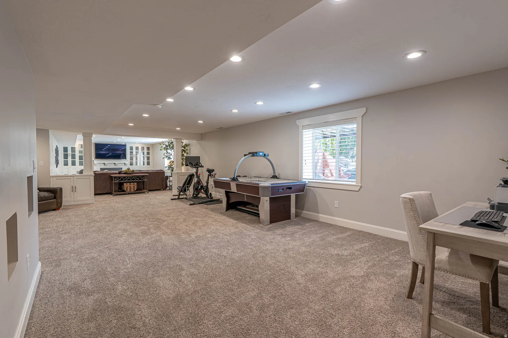 Spacious lower-level area featuring recessed lighting, new neutral carpeted floor, and a bright window with white blinds and trim