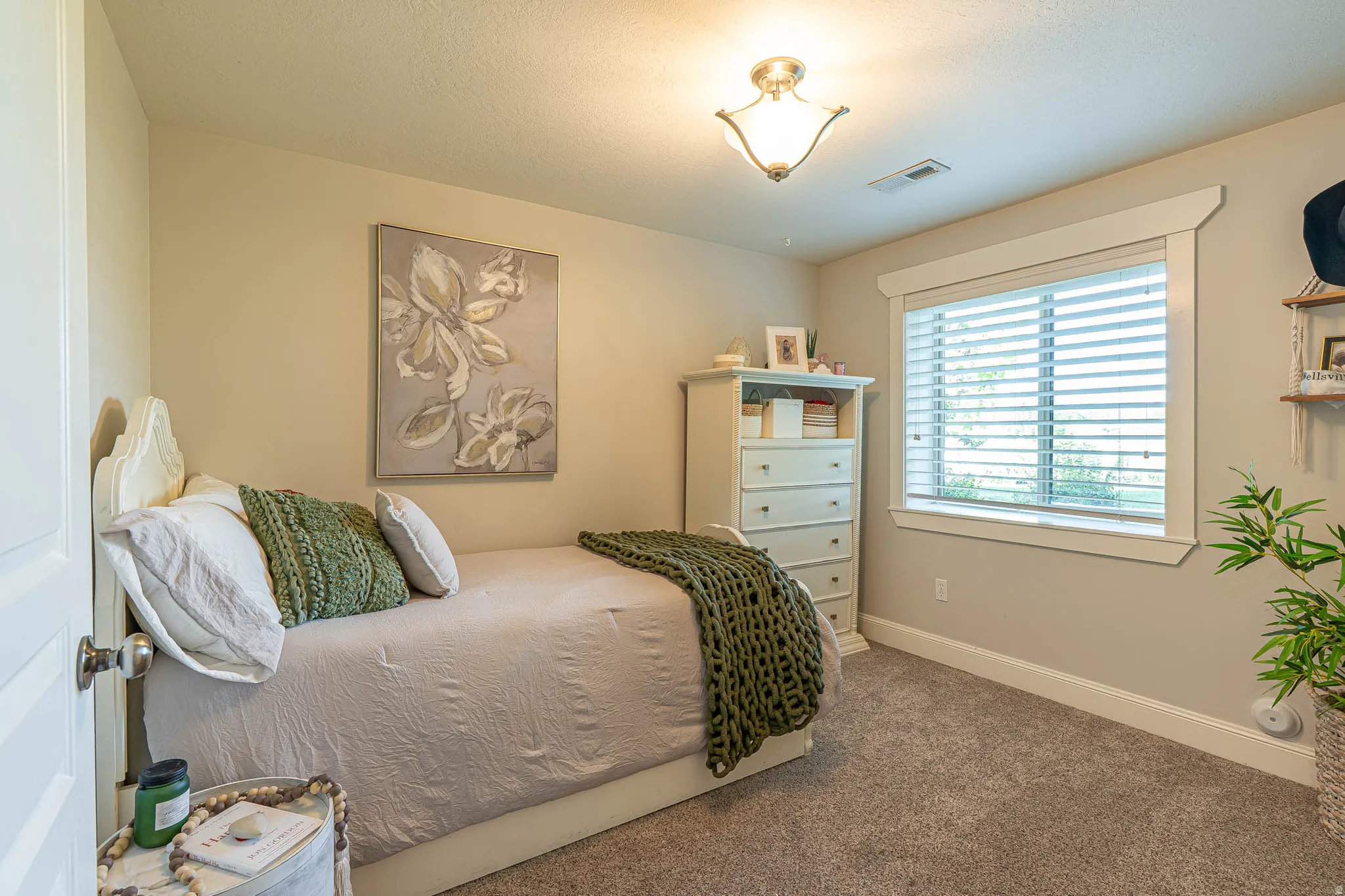Basement bedroom featuring neutral wall tones, textured carpeting, and a window with white blinds