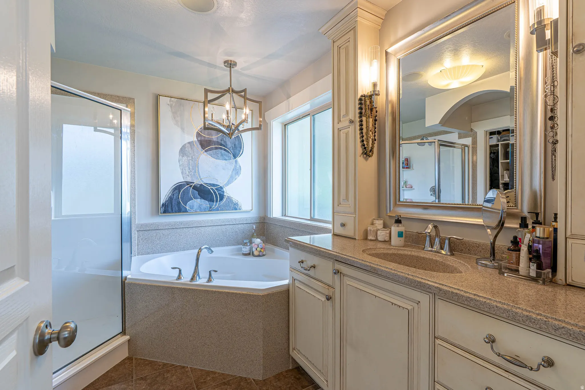 Primary bathroom featuring a corner soaking tub with jets, separate glass-enclosed shower, vanity with undermount sink, and new recessed lighting