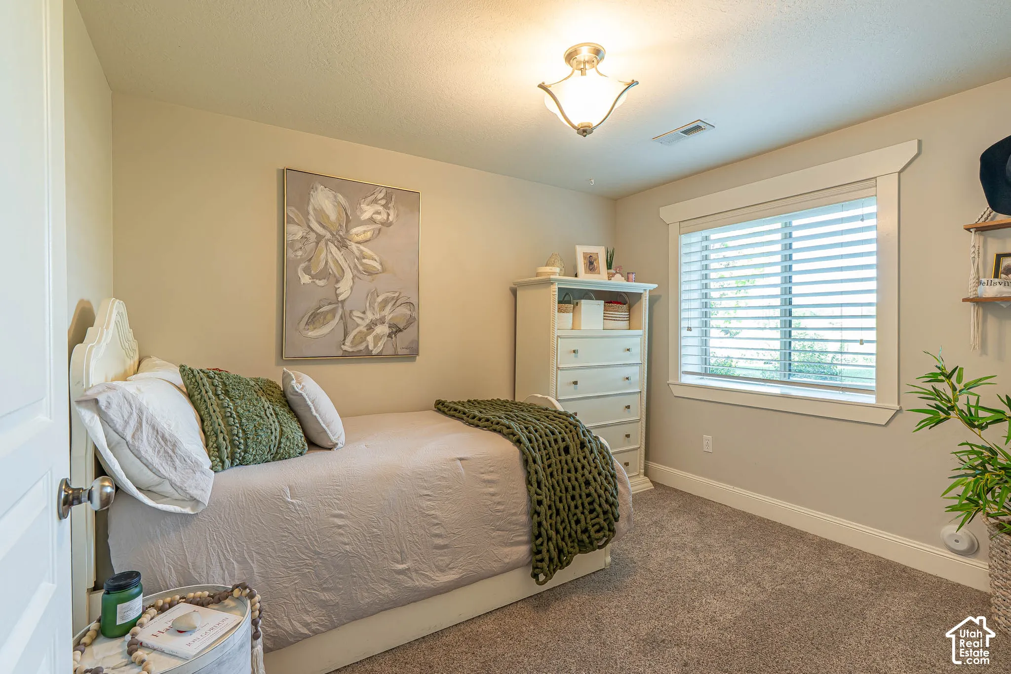 Basement bedroom featuring neutral wall tones, textured carpeting, and a window with white blinds