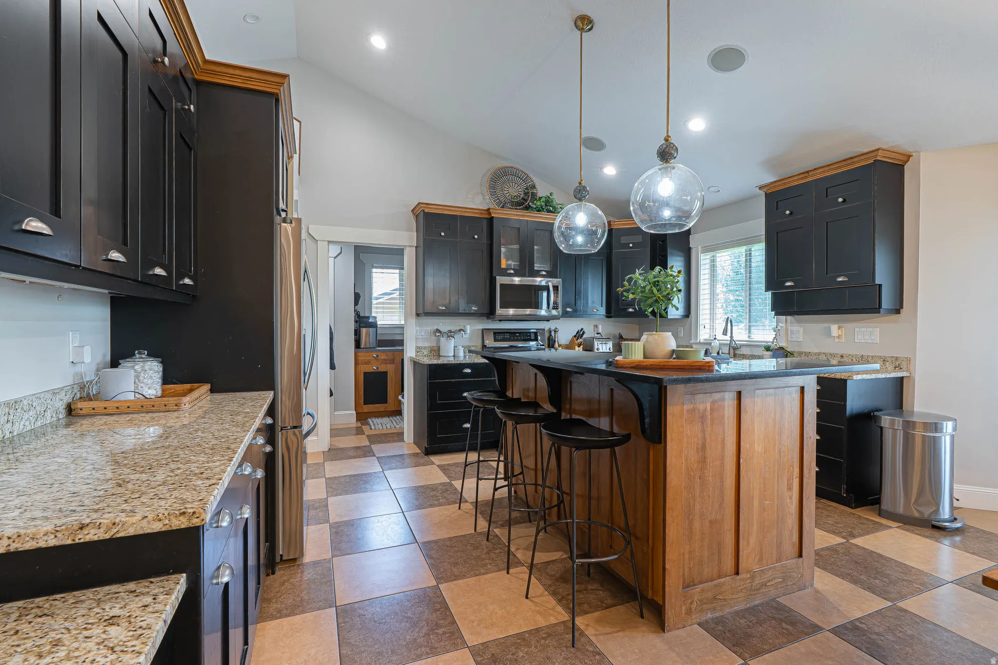 Kitchen featuring a central island with wood paneling and dark granite countertops, complemented by new pendant lighting