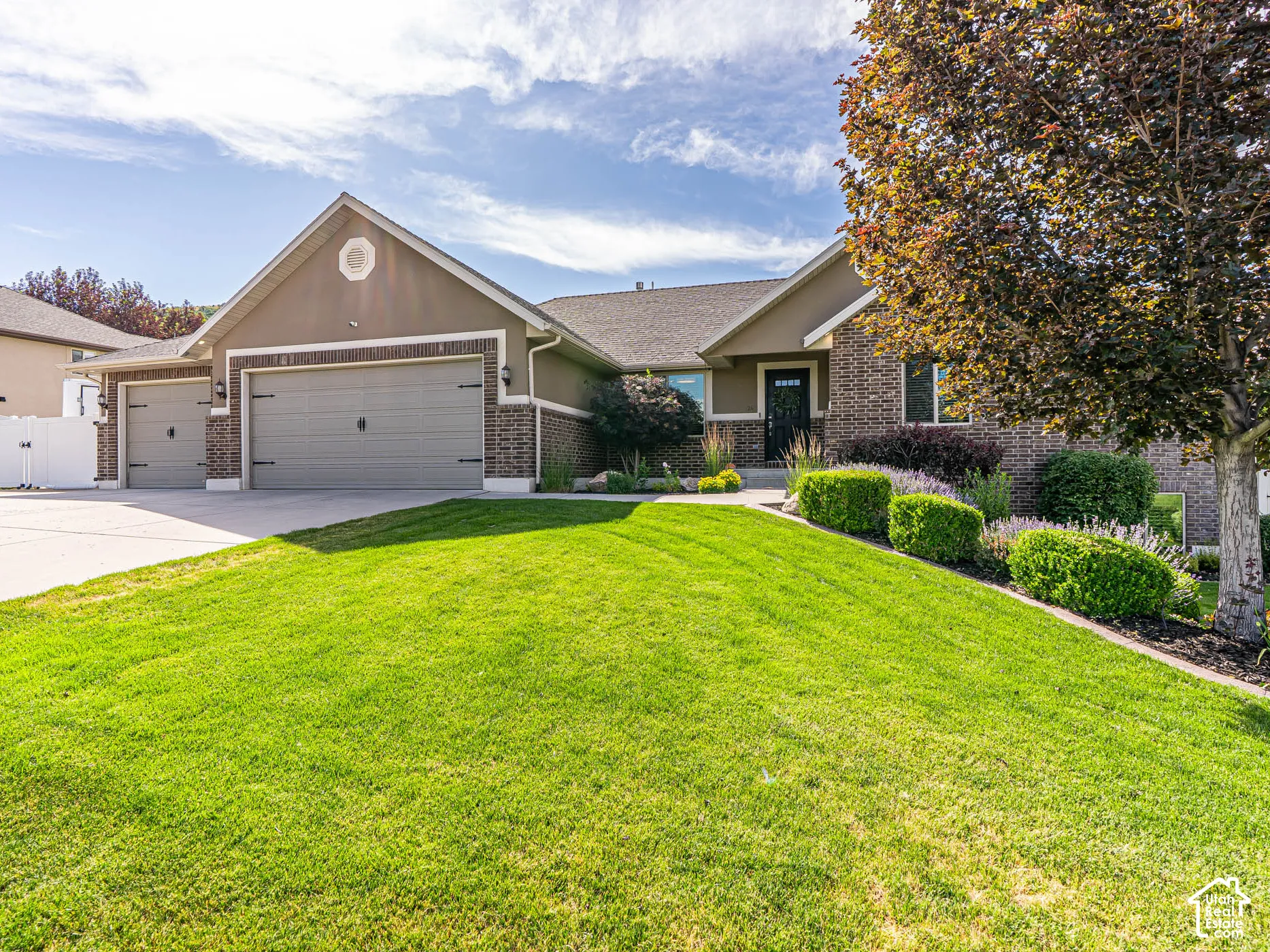 Contemporary ranch-style home featuring a brick and stucco exterior, a three-car garage, and a concrete driveway