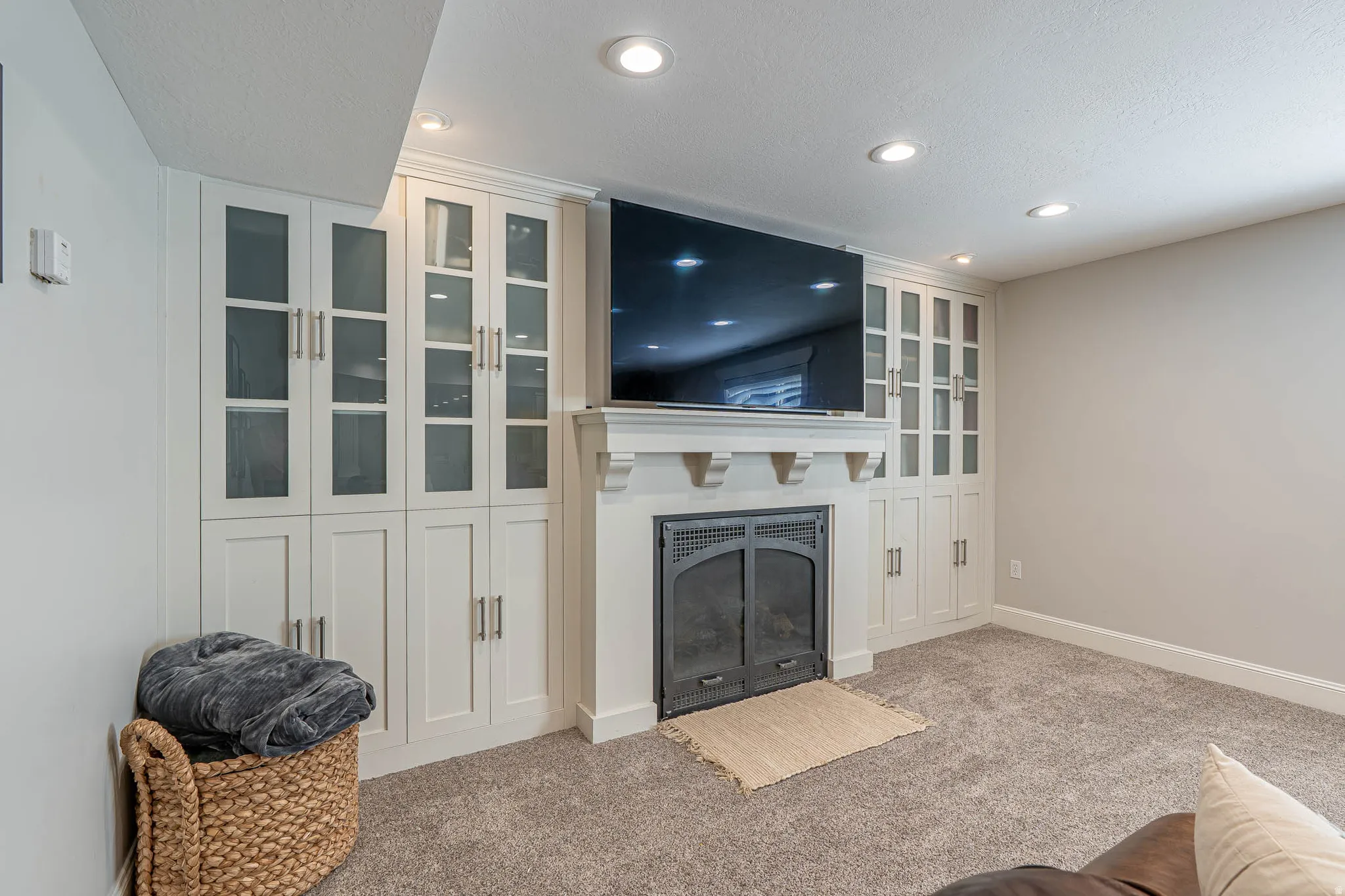 Built-in entertainment center featuring a fireplace with an arched firebox, extensive cabinetry with glass and solid panel doors, and recessed lighting