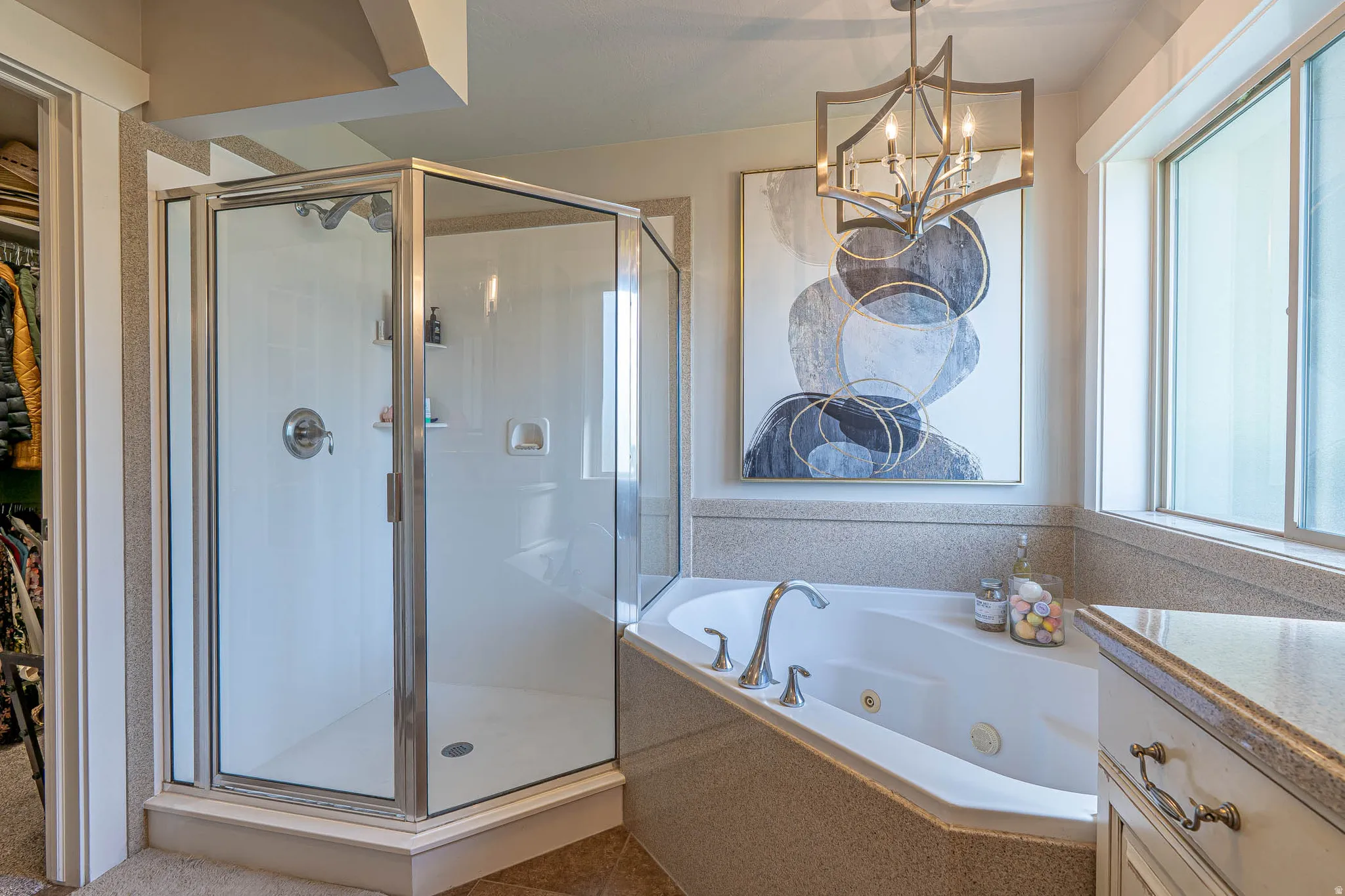 Spacious bathroom featuring a glass-enclosed shower, a built-in soaking tub with deck-mounted fixtures, and a vanity with a light-toned countertop