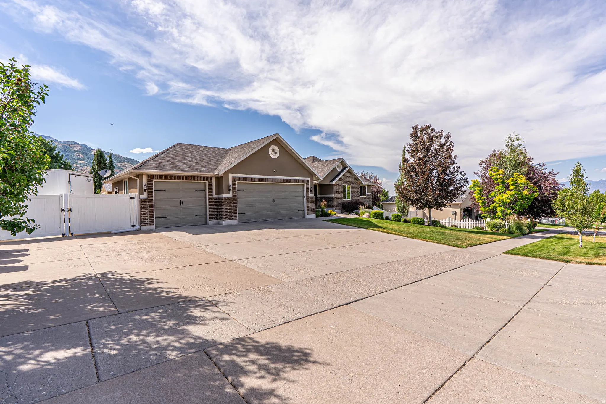 Expansive paved driveway for all your paring needs leading to a three-car garage with carriage-style doors