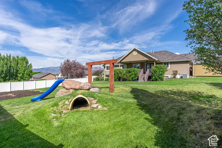 Expansive backyard featuring a manicured lawn, a white privacy fence, room for garden and a stucco exterior with a covered patio
