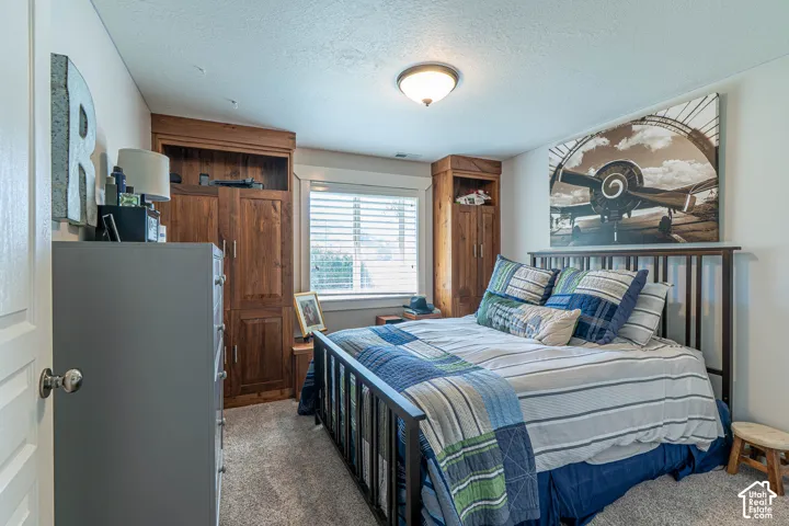 Basement bedroom featuring built-in wood cabinetry, a window with horizontal blinds, and a flush-mount ceiling light fixture
