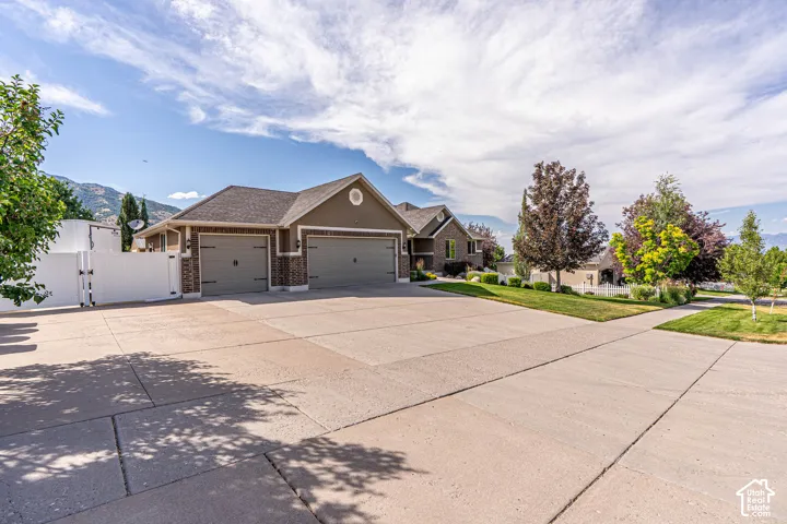 Expansive paved driveway for all your paring needs leading to a three-car garage with carriage-style doors