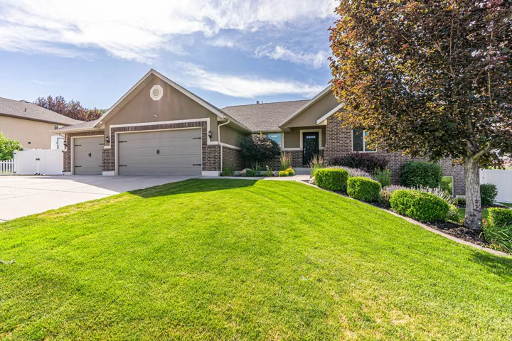 Contemporary ranch-style home featuring a brick and stucco exterior, a three-car garage, and a concrete driveway