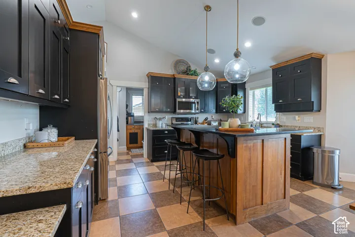 Kitchen featuring a central island with wood paneling and dark granite countertops, complemented by new pendant lighting