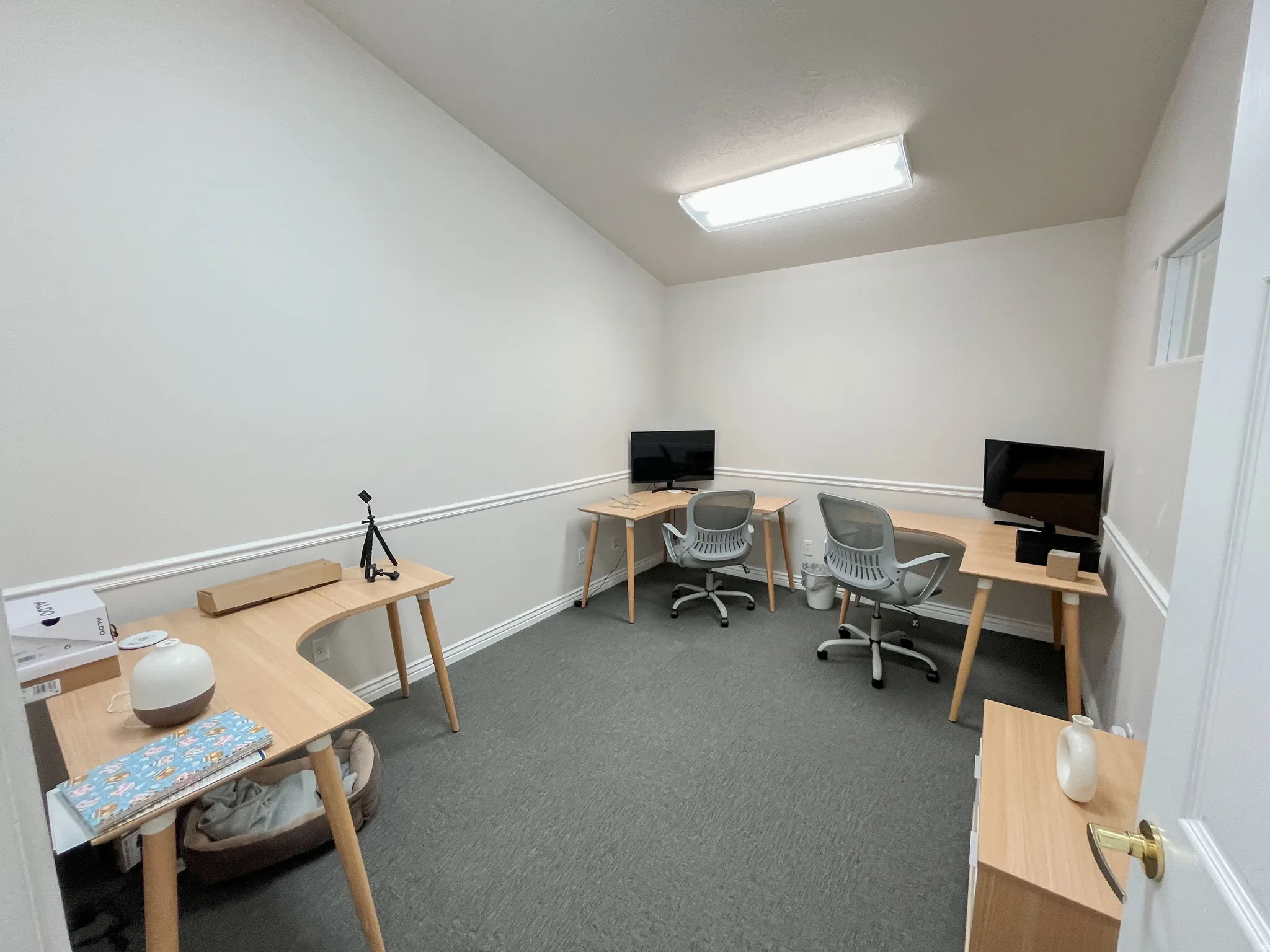 Dedicated office space featuring a vaulted ceiling, neutral wall tones, chair rail molding, and grey carpet