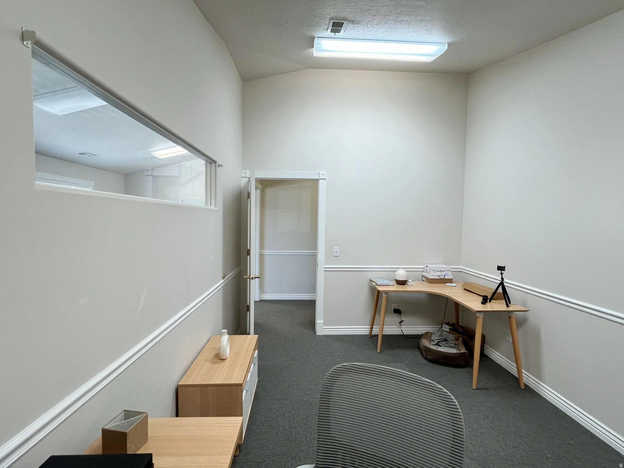 Interior room featuring a horizontal window opening and a doorway with a light wood-finish door frame