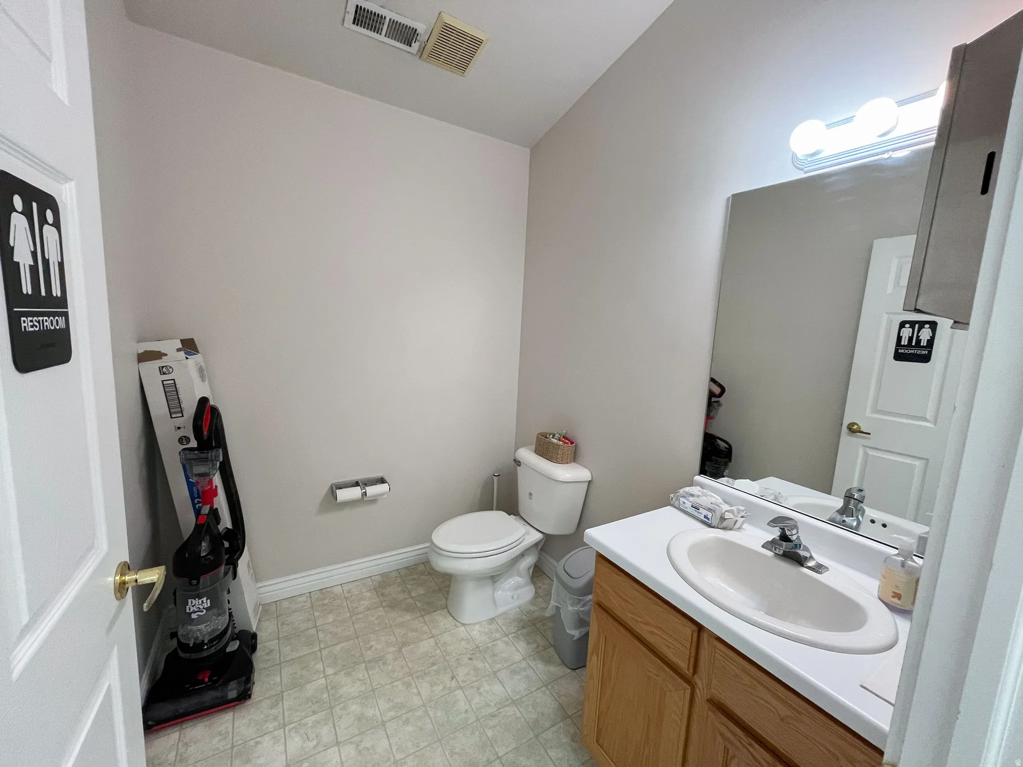 Bathroom featuring a single vanity with wood-finish cabinetry, a white countertop, and an oval undermount sink